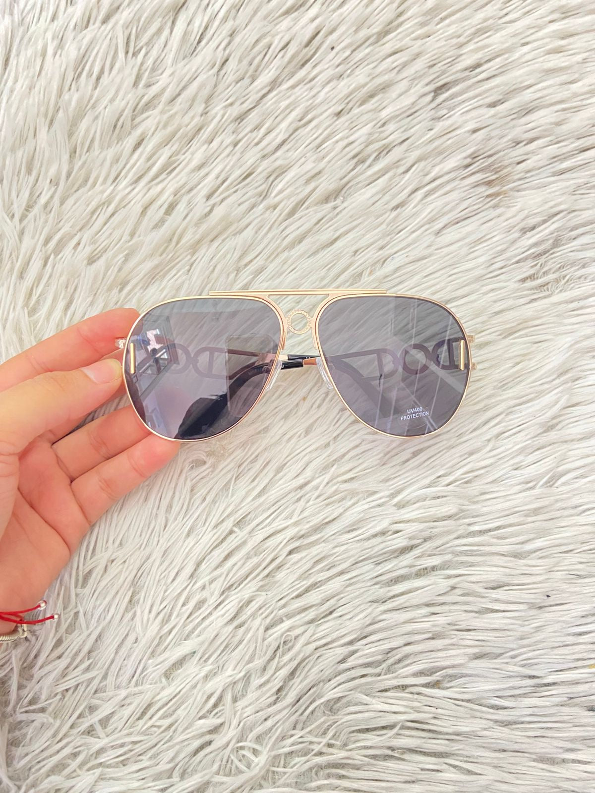 Lentes con montura en color dorado y detalles en los lados y micas oscuras