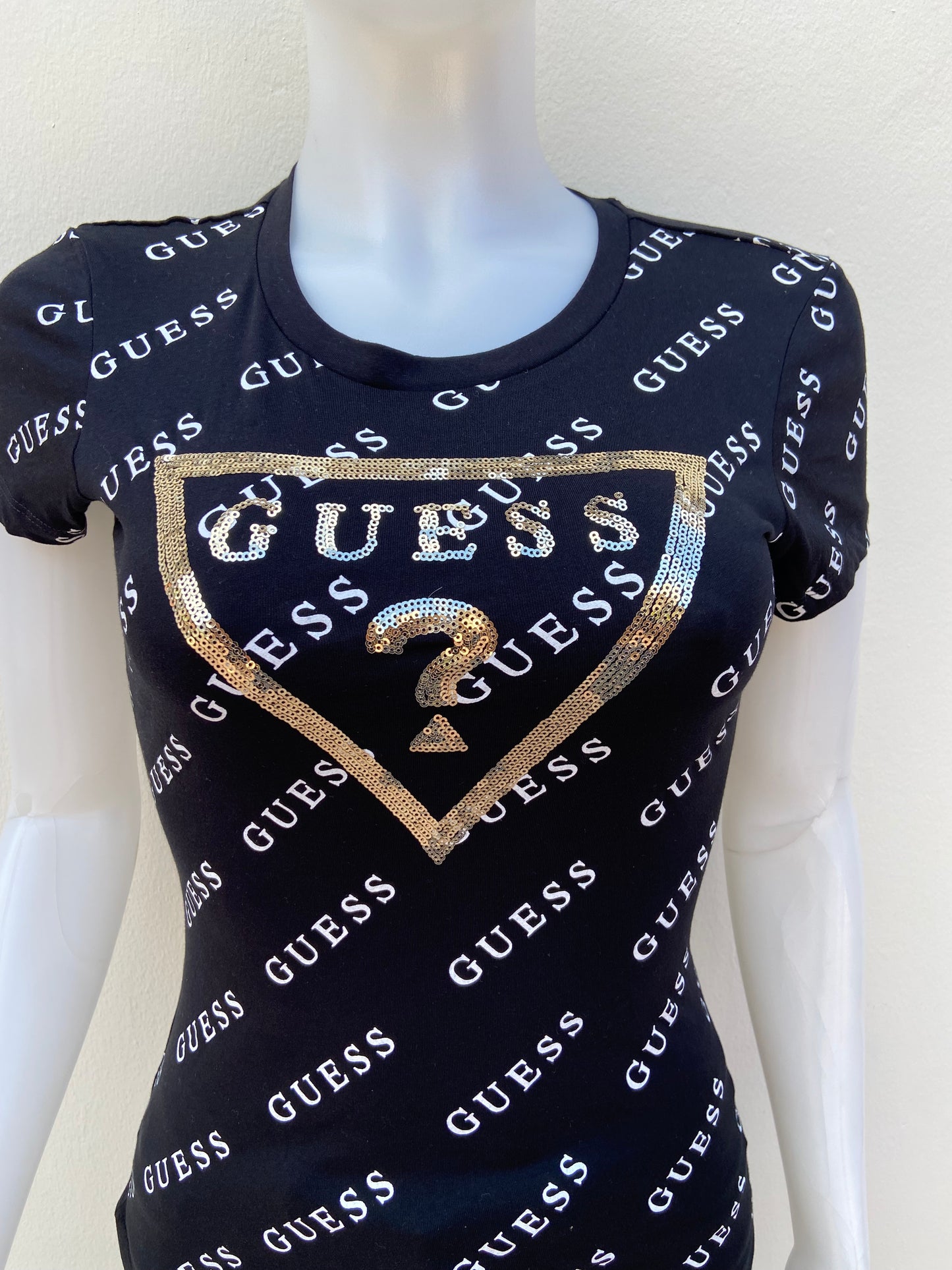 T-shirt GUESS original, negro con estampado de otras GUESS en blanco y triángulo en dorado con su logo.