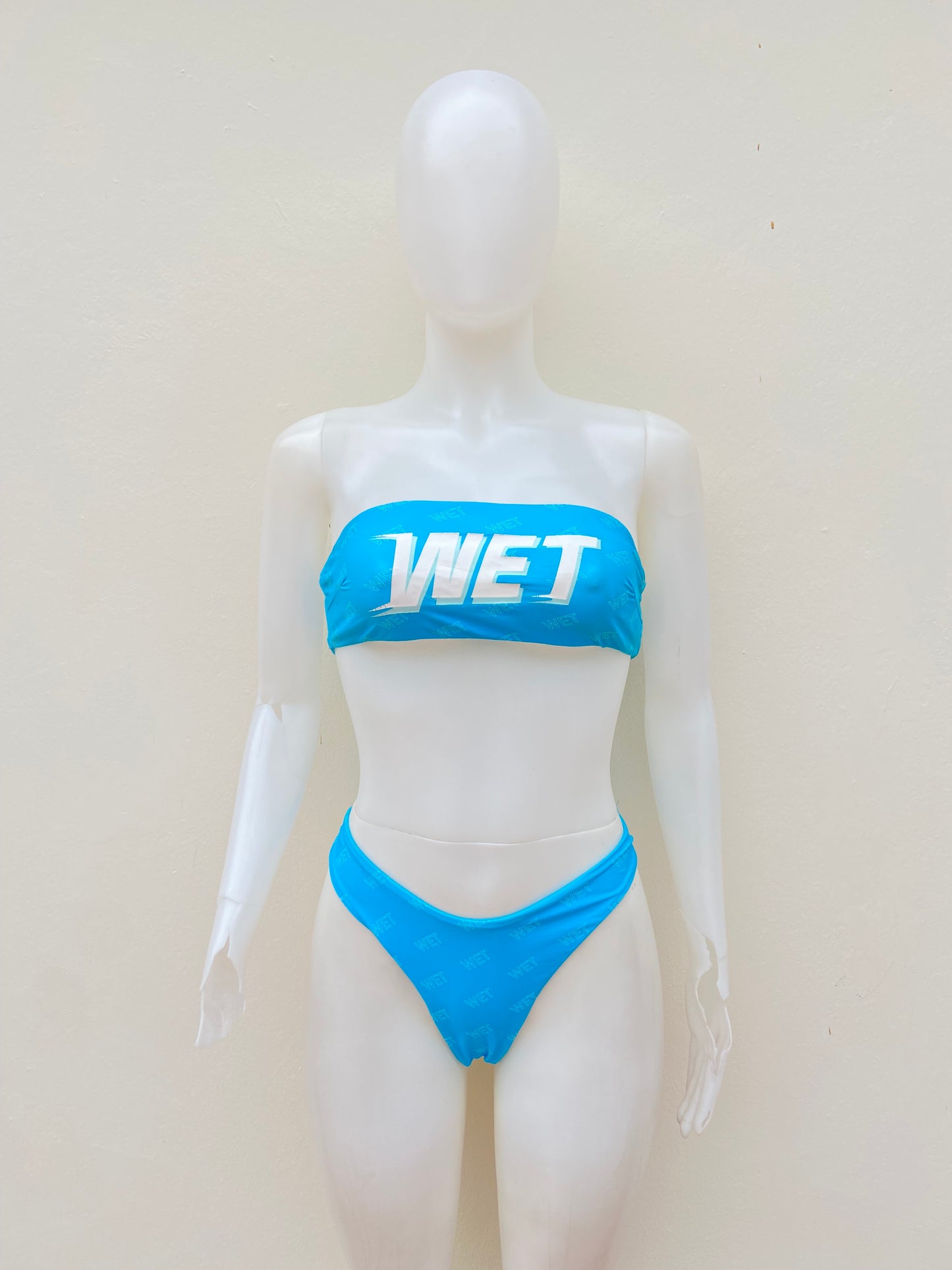 Biquini, azul claro con letras WET en blanco, strapless, 2 piezas.