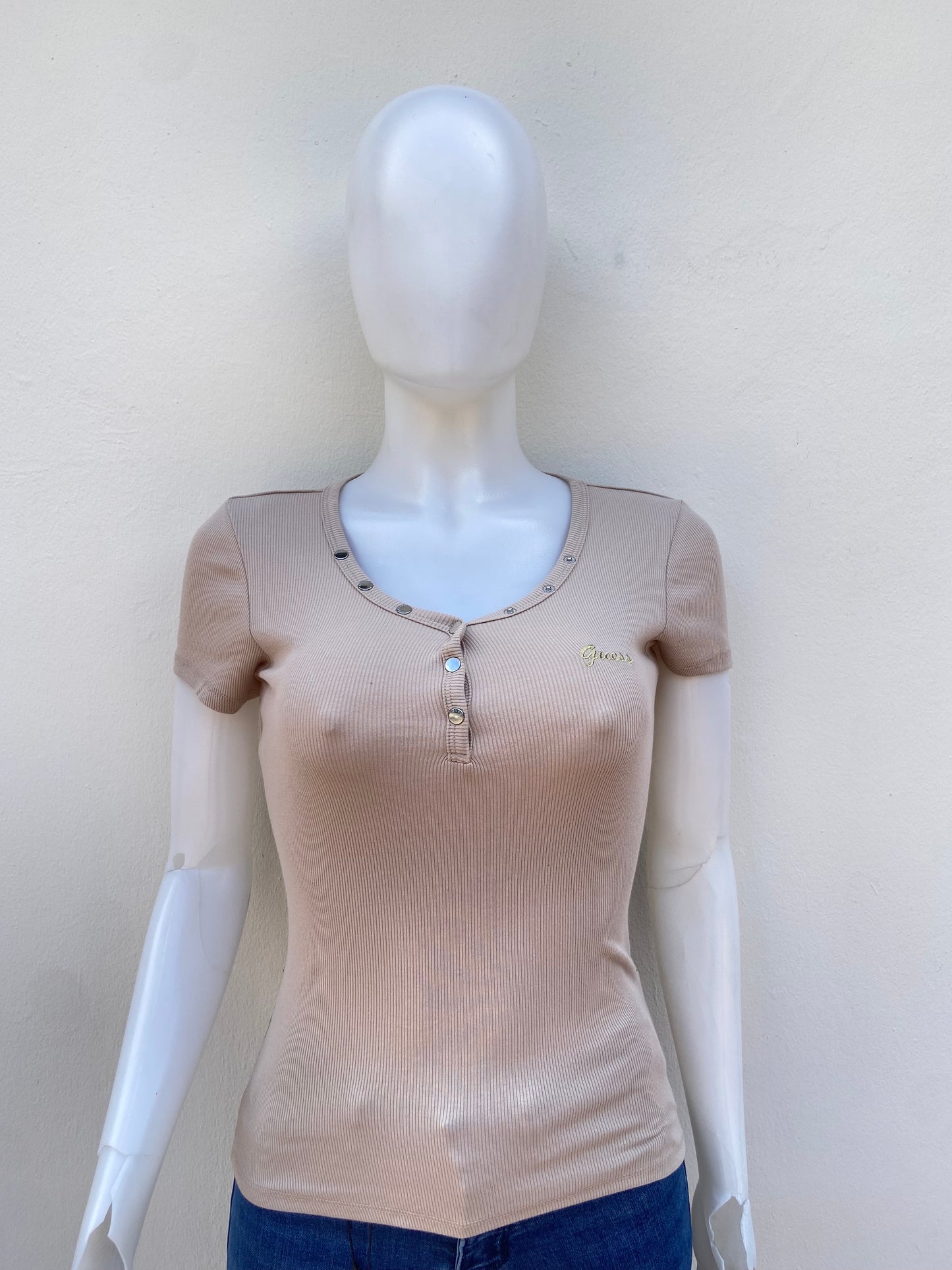 T-shirt GUESS original, crema ( beige ) con letras GUESS en cursivas en dorado y botones plateados.