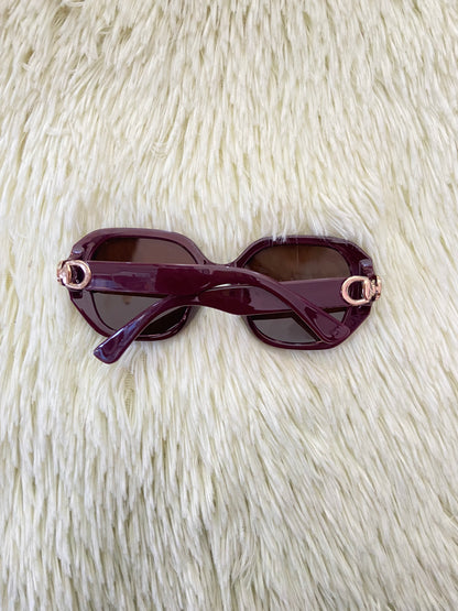 Lentes, rojo vino con micas oscuras y detalles dorado en los lados, con protección UV 100-400.