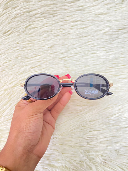 Lentes, negros con montura dorada ovalados, con protección UV 100% Polycarbonate.