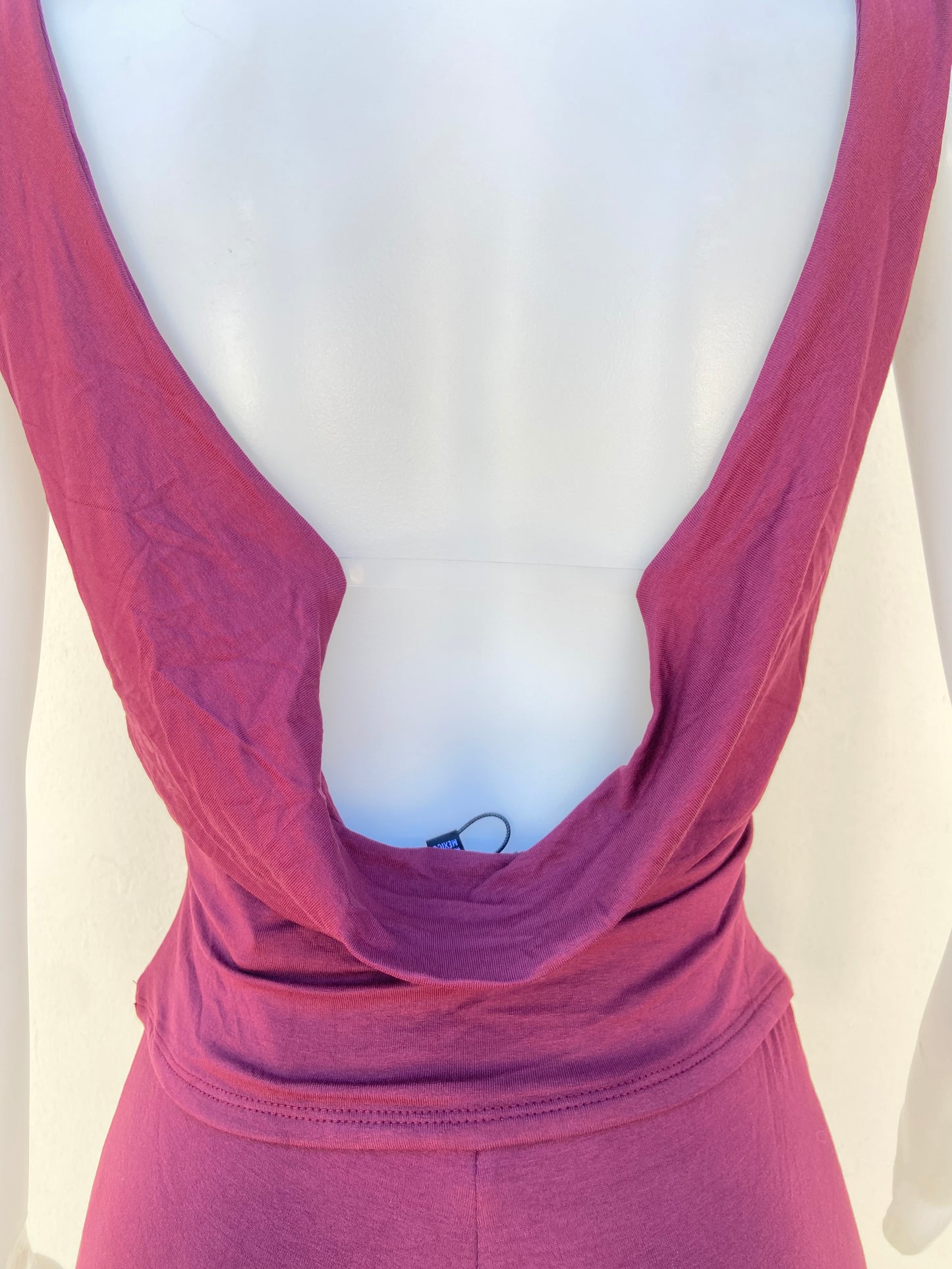 Conjunto, rojo vino de pantalon y top con Cadena colgante  en dorado en frente y escote en la espalda.