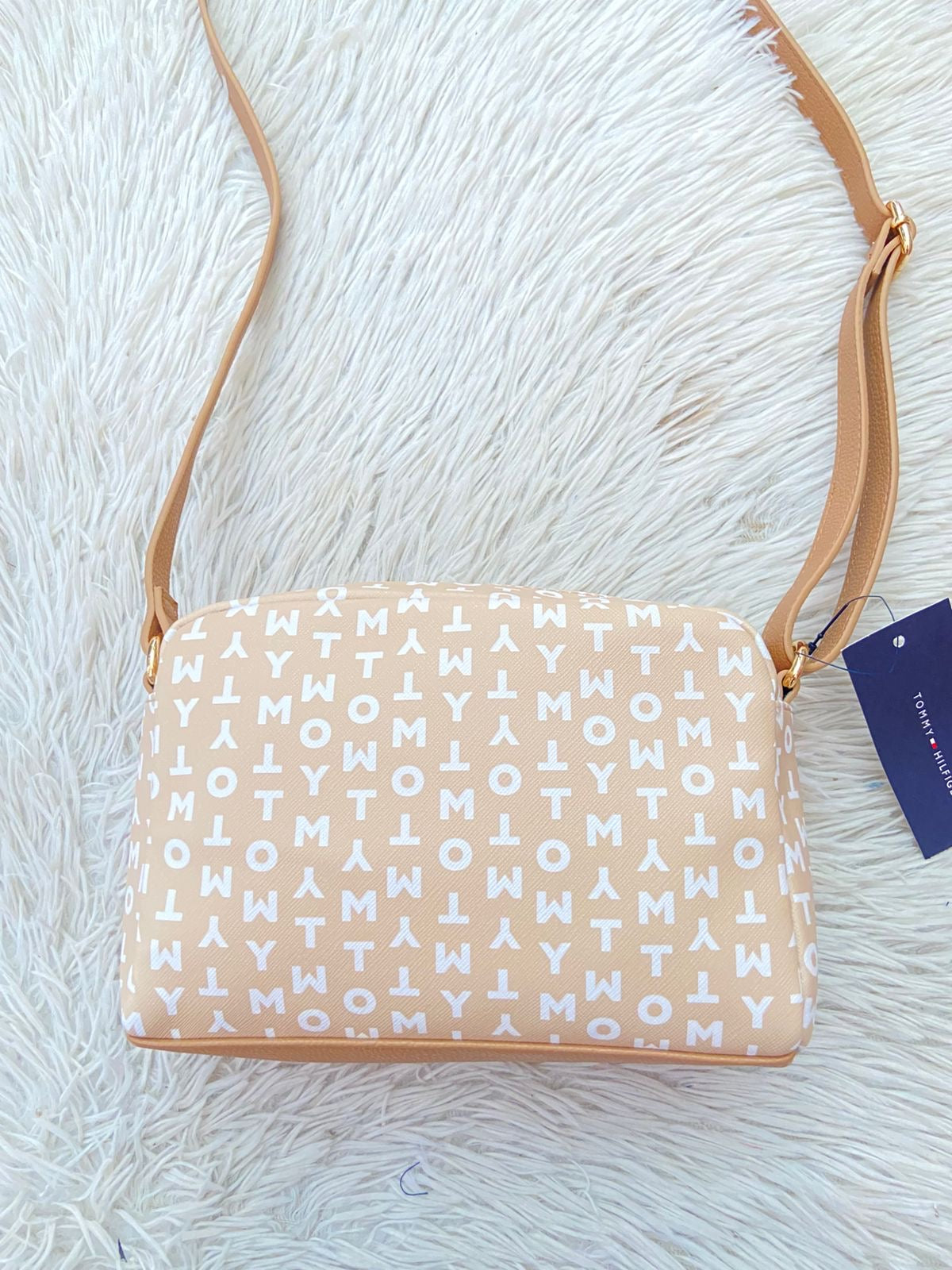 Cartera TOMMY HILFIGER original crema con estampado de letras TOMMY y banda de color rojo, azul y blanco y placa TH en dorado.