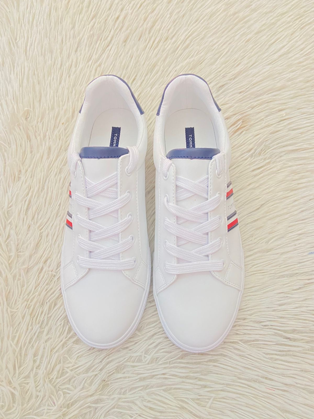 Tenis Tommy Hilfiger Original en color blanco con bandera de la en los lados y letra Tommy en el medio