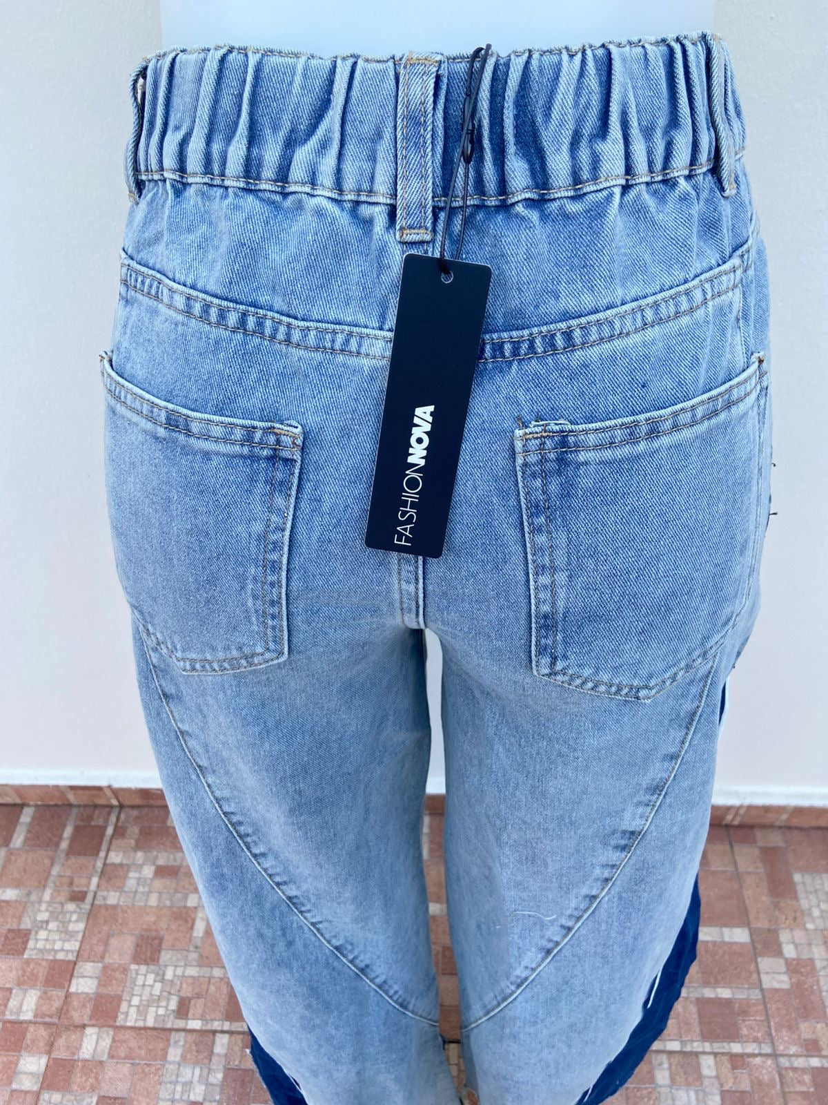 Pantalon jean azul claro con degradado blanco, tela azul oscura con blanco abajo, rotos y con pretina ajustable, ancho.