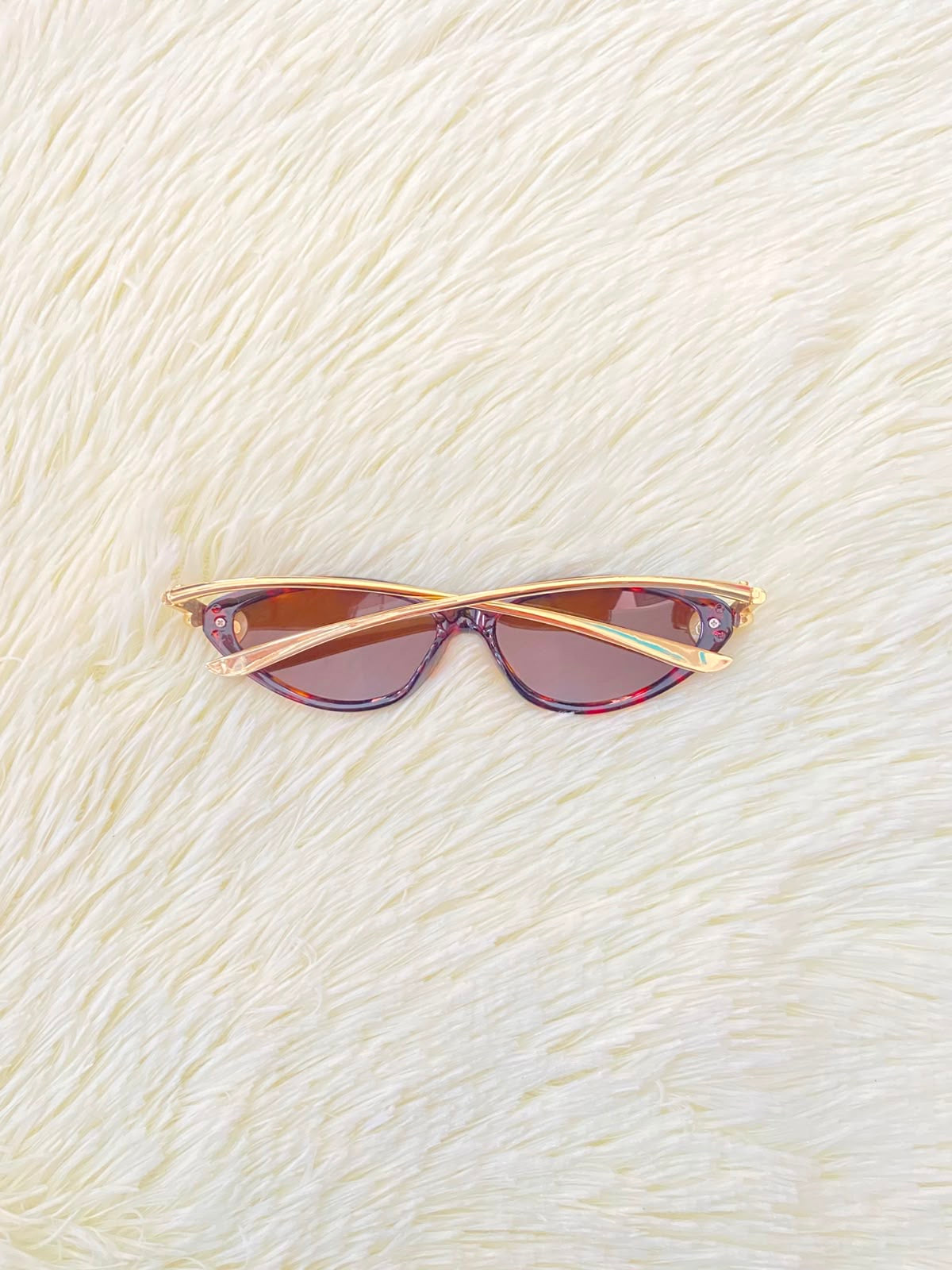 Lentes, montura con estampado de animal print, micas marrones y patillas doradas.