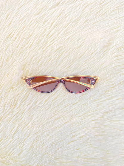 Lentes, montura con estampado de animal print, micas marrones y patillas doradas.