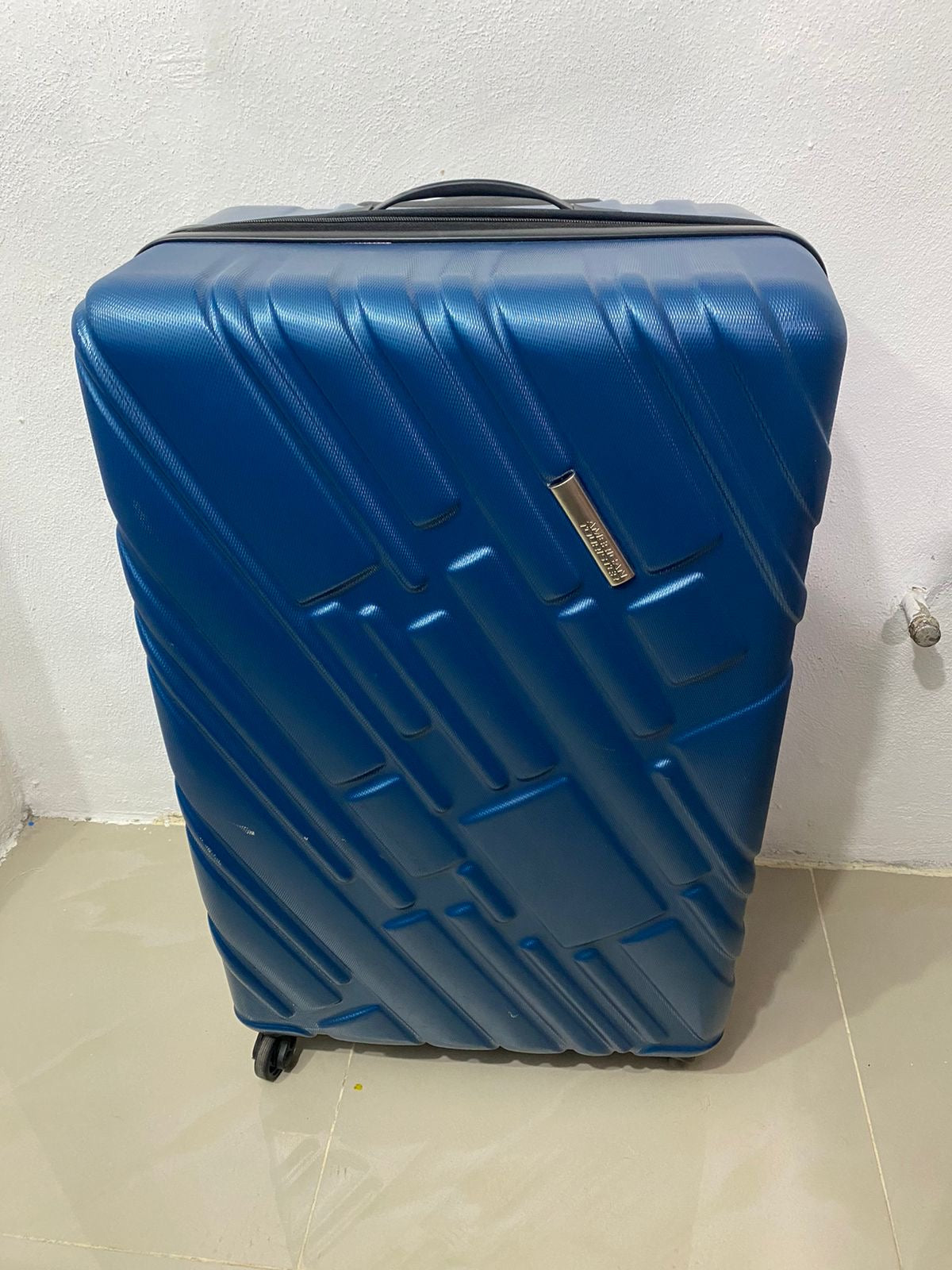 Maleta American Tourister original azul con negro y placa de la marca en frente.