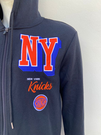 Abrigo NBA original NY KNICKS  negro con zipper y letras NY en color naranja al lado.