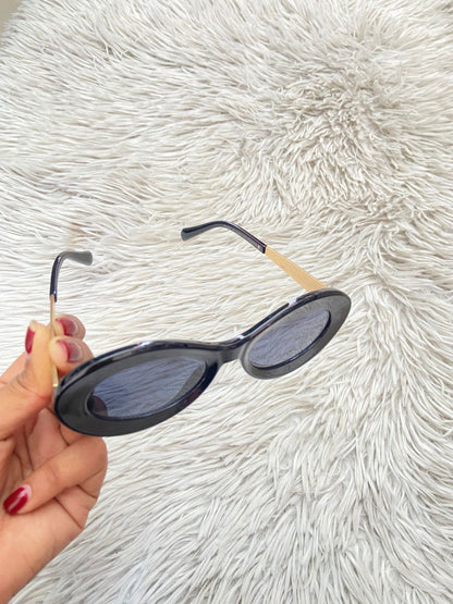 Lentes, diseñados con protección UV 100-400 para proteger tu visión. Negro con montura en dorado y micas en forma de óvalo.