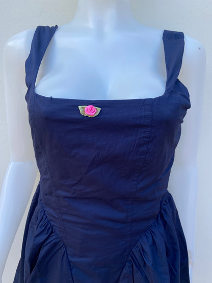 Vestido, algodón orgánico en azul marino ( NAVY) con flor rosada en frente.