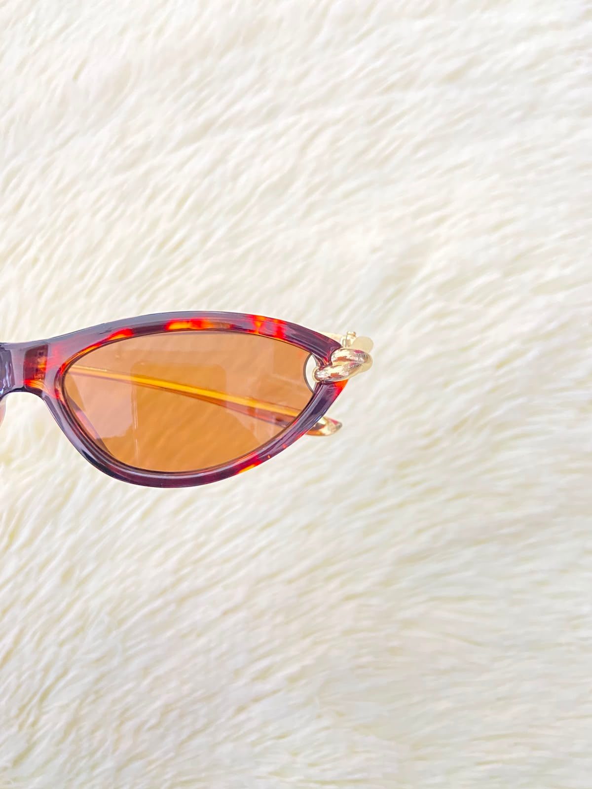 Lentes, montura con estampado de animal print, micas marrones y patillas doradas.