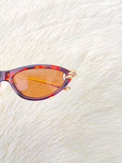 Lentes, montura con estampado de animal print, micas marrones y patillas doradas.