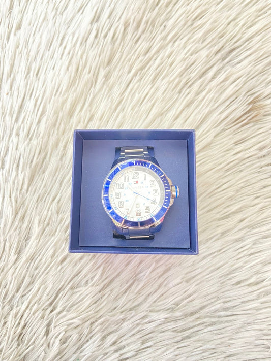Reloj Tommy Hilfiger Original en color plateado con azul en el borde numeros plateados y logotigo de la marca en el fondo