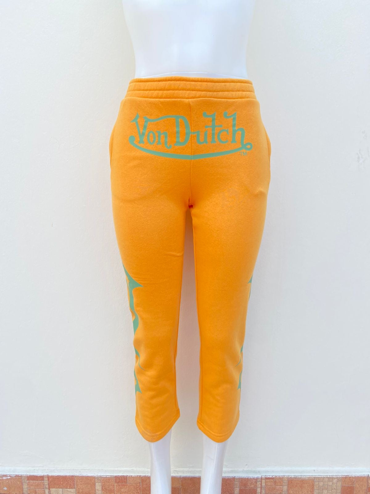 Pantalon VON DUTCH original Amarillo mostaza con letras de la marca en verde.