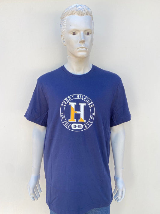 T-shirt TOMMY HILFIGER, Original en color azul marino con letra de la marca en un circulo al frente y una H en el centro en color amarillo y blanco.