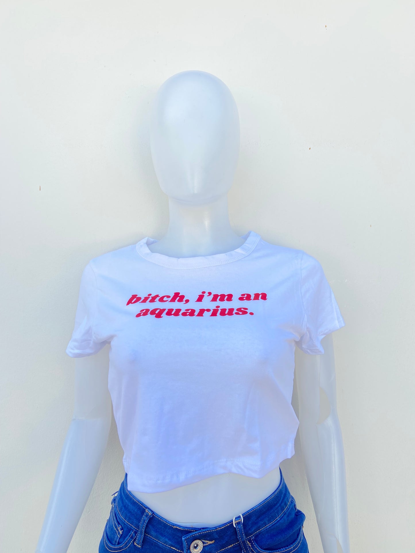 Top, blanco con letras BITCH I’M AN AQUARIUS ( Perra, soy acuario ) en rojo.