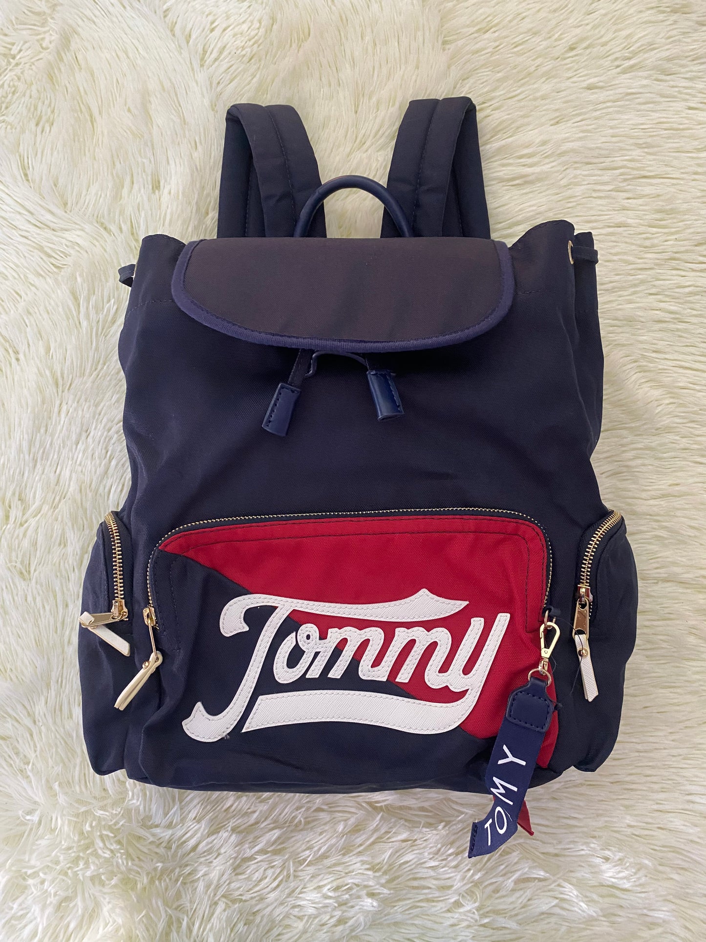 Mochila Tommy Hilfiger original en color azul marino, nombre TOMMY en grande en un bolsillo con el fondo rojo, varios compartimentos, súper espacioso.