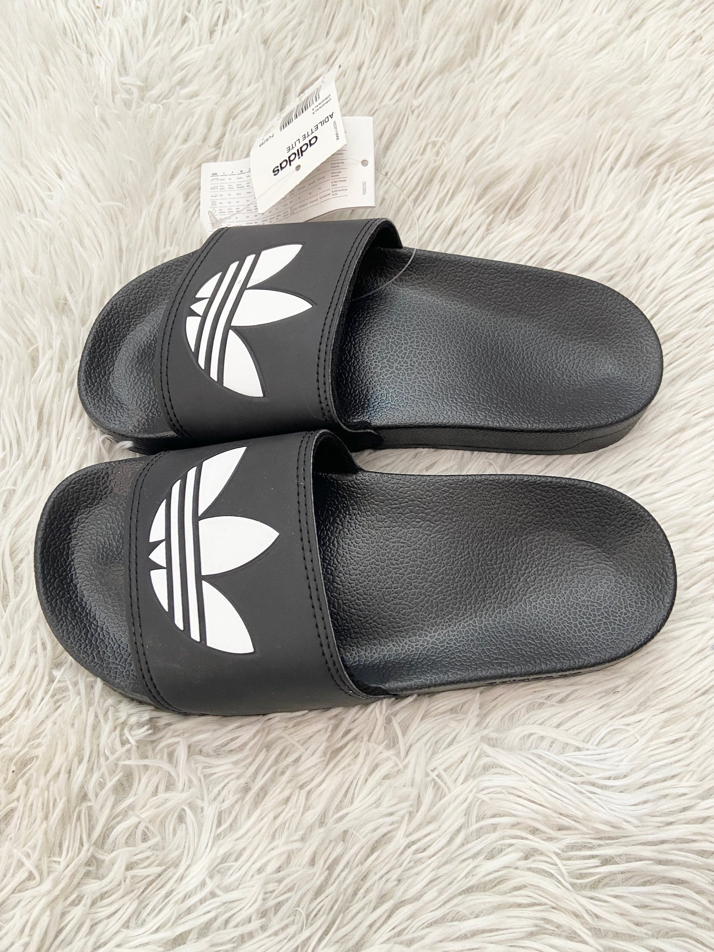 Sandalias Adidas original negra con logotipo en frente de la marca en blanco.
