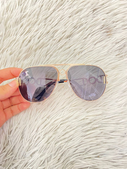 Lentes con protección UV 100-400 para proteger tu visión. Con montura en dorado y detalles en los lados.