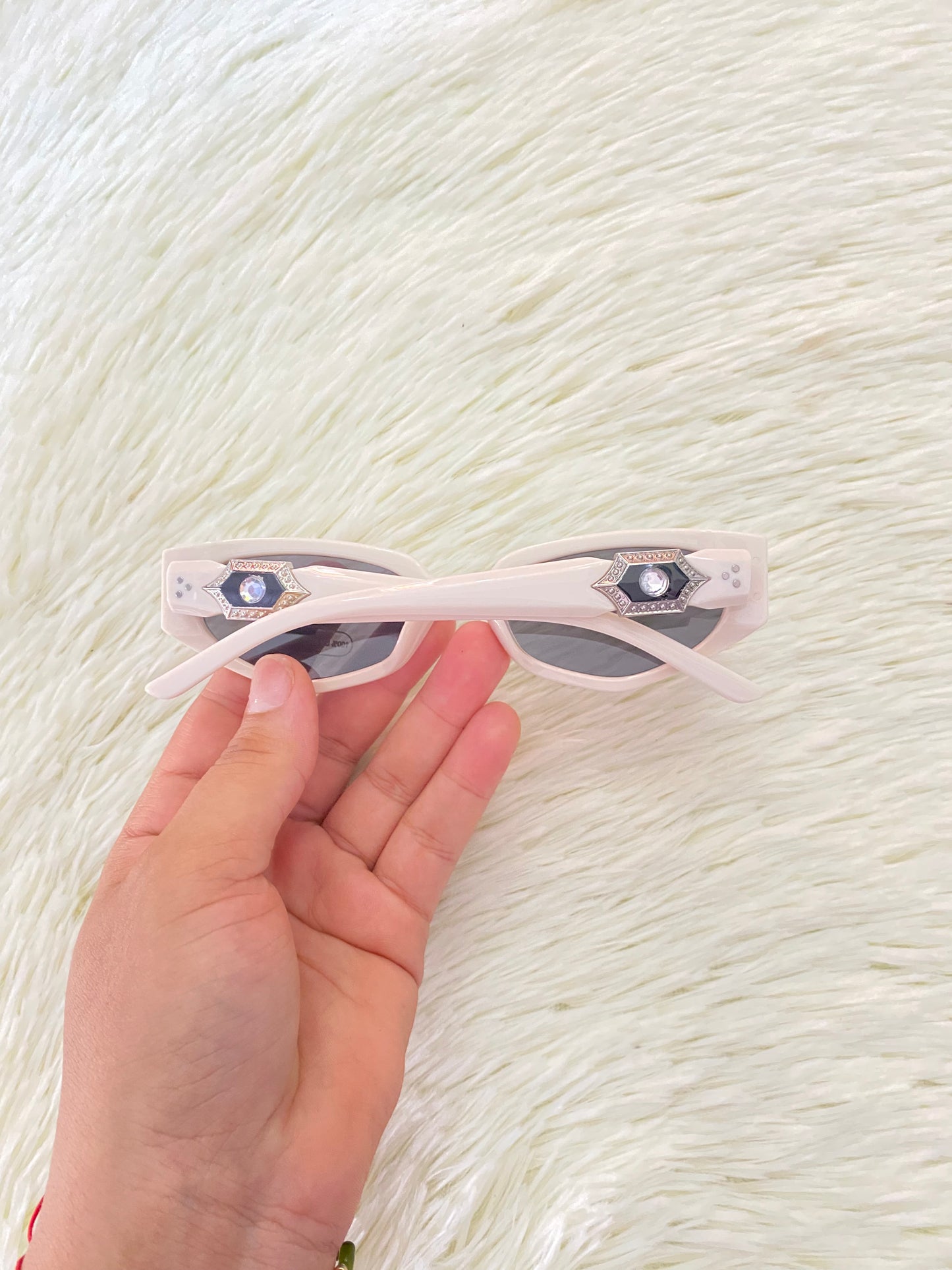 Lentes color blanco/hueso con micas oscuras con detalle plateado con negro atrás.