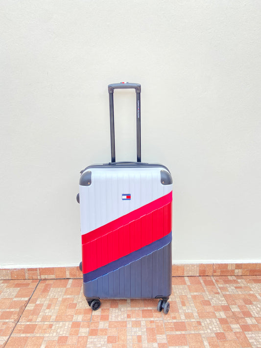 Maleta TOMMY HILFIGER original, negra con diseño en color blanco, rojo y azul marino al frente y logotipo de la marca.