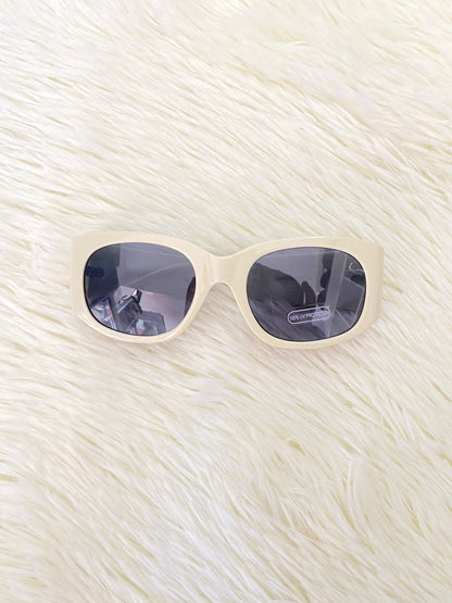 Lentes color crema con estampado de hojas tropicales en las patillas, estilo rectangular, con protección UV 100%.