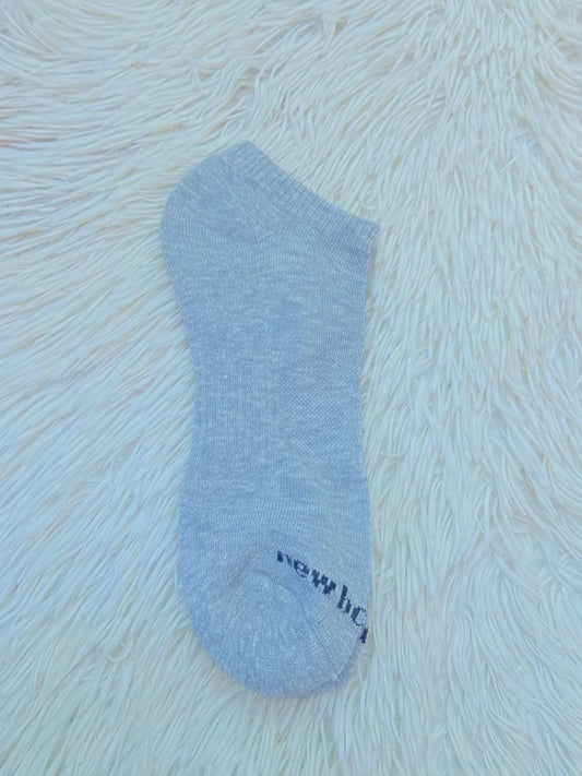 Medias NEW BALANCE original gris clara lisa con pequeña letras de la marca en la parte inferior.