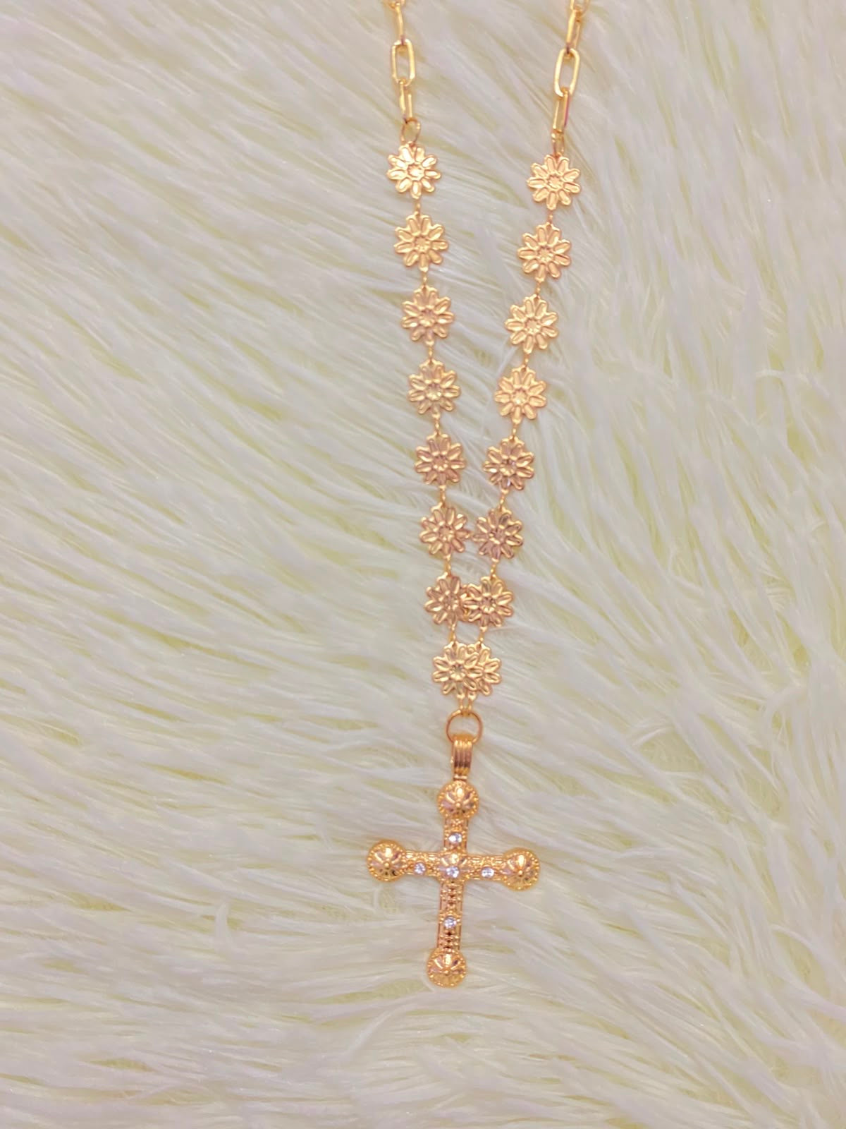 Cadena, dorada con dije en forma de cruz.