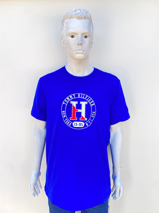 T-shirt TOMMY HILFIGER Original en color azul con letra de la marca en un circulo al frente y una H en el centro.