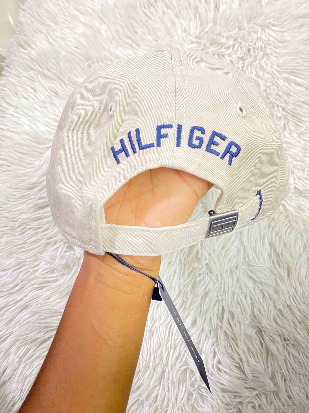 Gorra Tommy Hilfiger original crema con pequeño logotipo Tommy en la esquina y letras HILFIGER en azul.