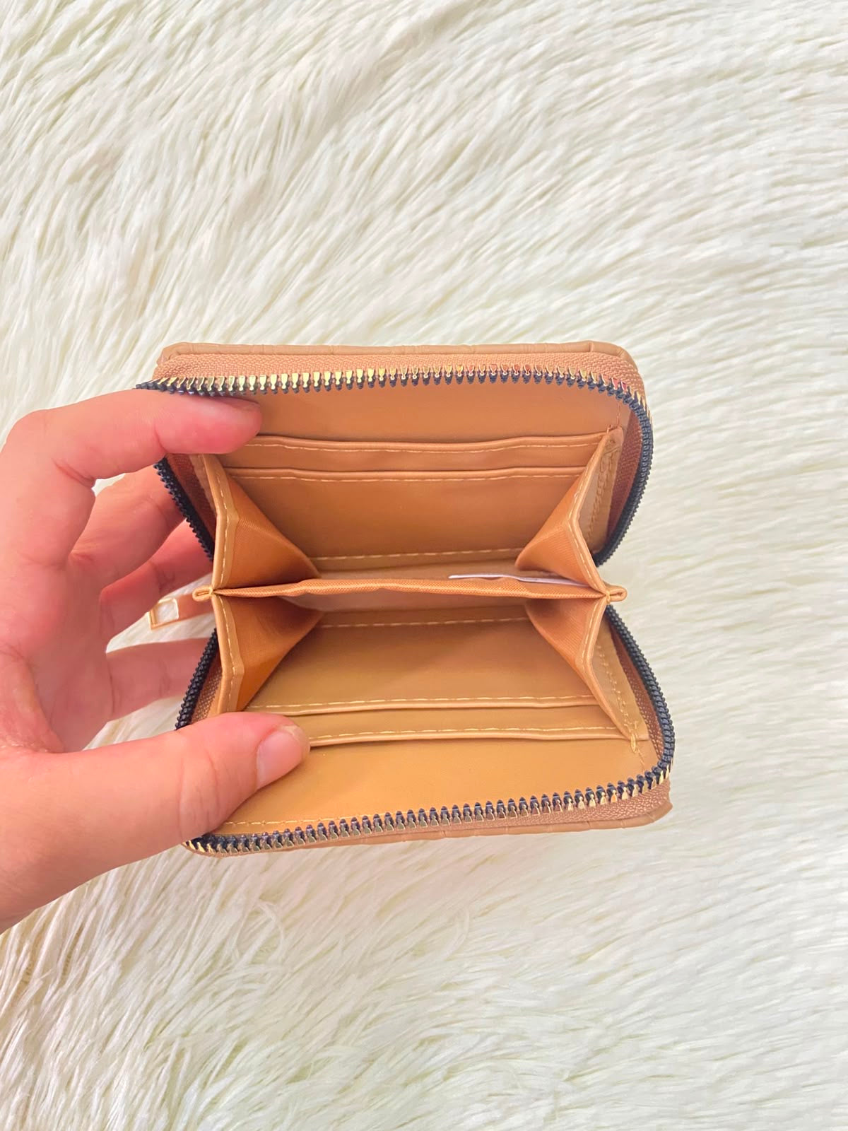 Monedero color marrón con diseño acolchado, cierre de zíper y espacio para tarjetas y más.