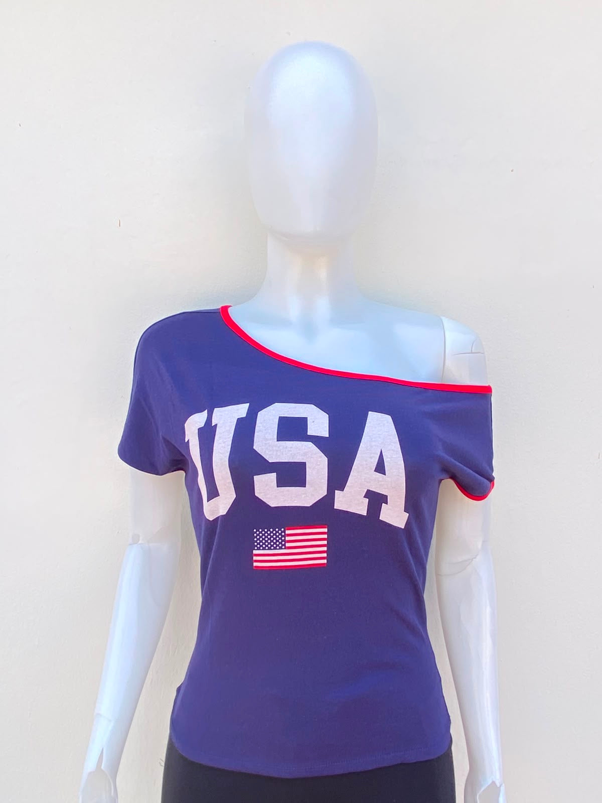 T-shirt/top color azul marino con letra USA y bandera al frente, con un hombro abajo y línea roja.