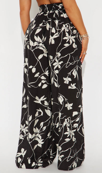 Pantalon Fashion Nova negro con estampados de flores blancas, estilo palazzo.