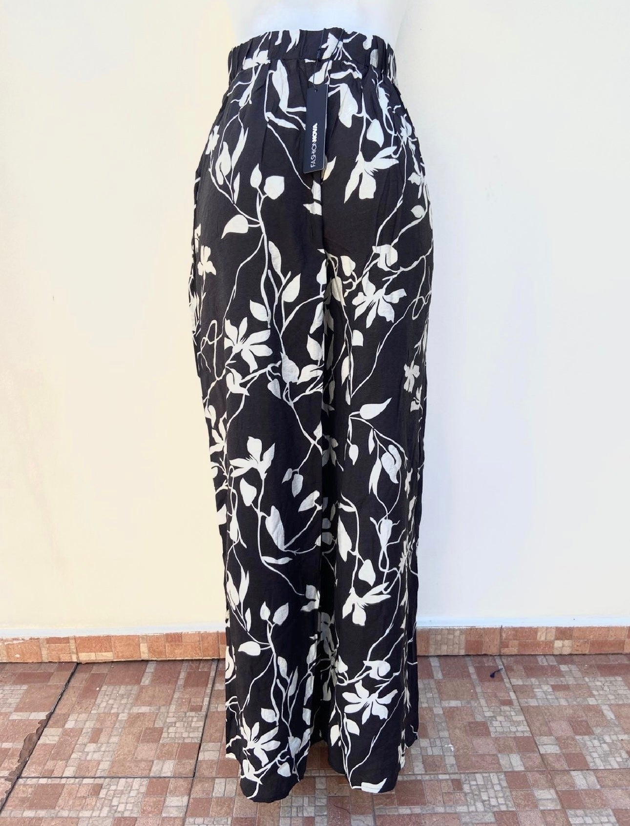 Pantalon Fashion Nova negro con estampados de flores blancas, estilo palazzo.