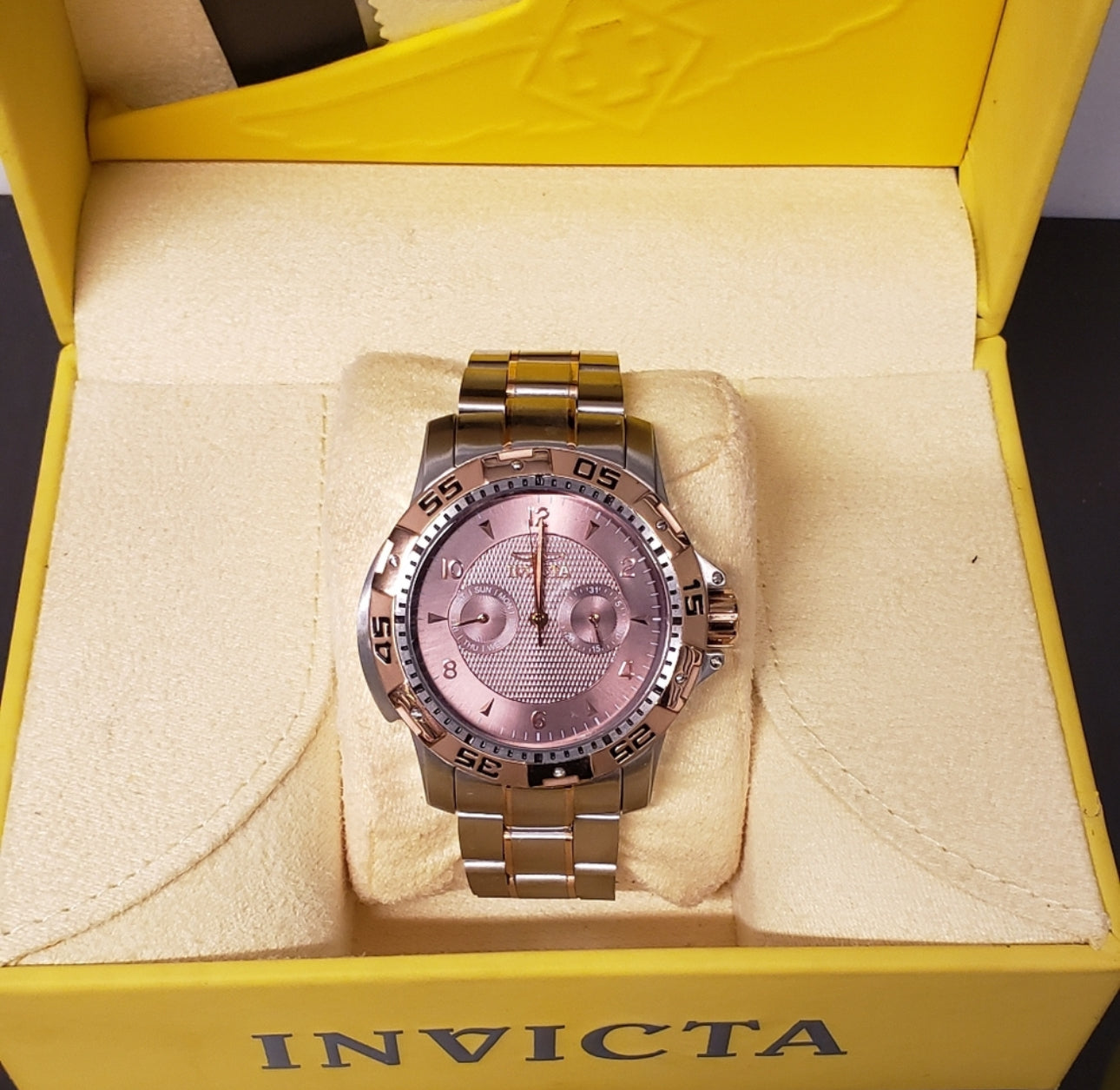 Reloj INVICTA original plateado con color bronce y detalles en color negro.