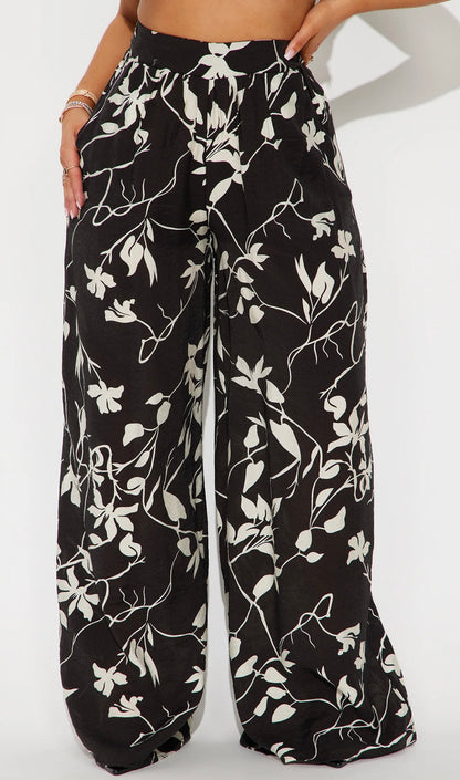 Pantalon Fashion Nova negro con estampados de flores blancas, estilo palazzo.
