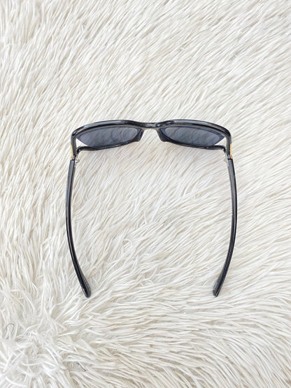 Lentes negro, ovalados, con detalle dorado en la esquina y micas claras PROTECCIÓN UV 100