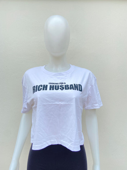 Top blanco, con letras negras “LOOKING FOR A RICH HU$BAND (buscando marido rico).