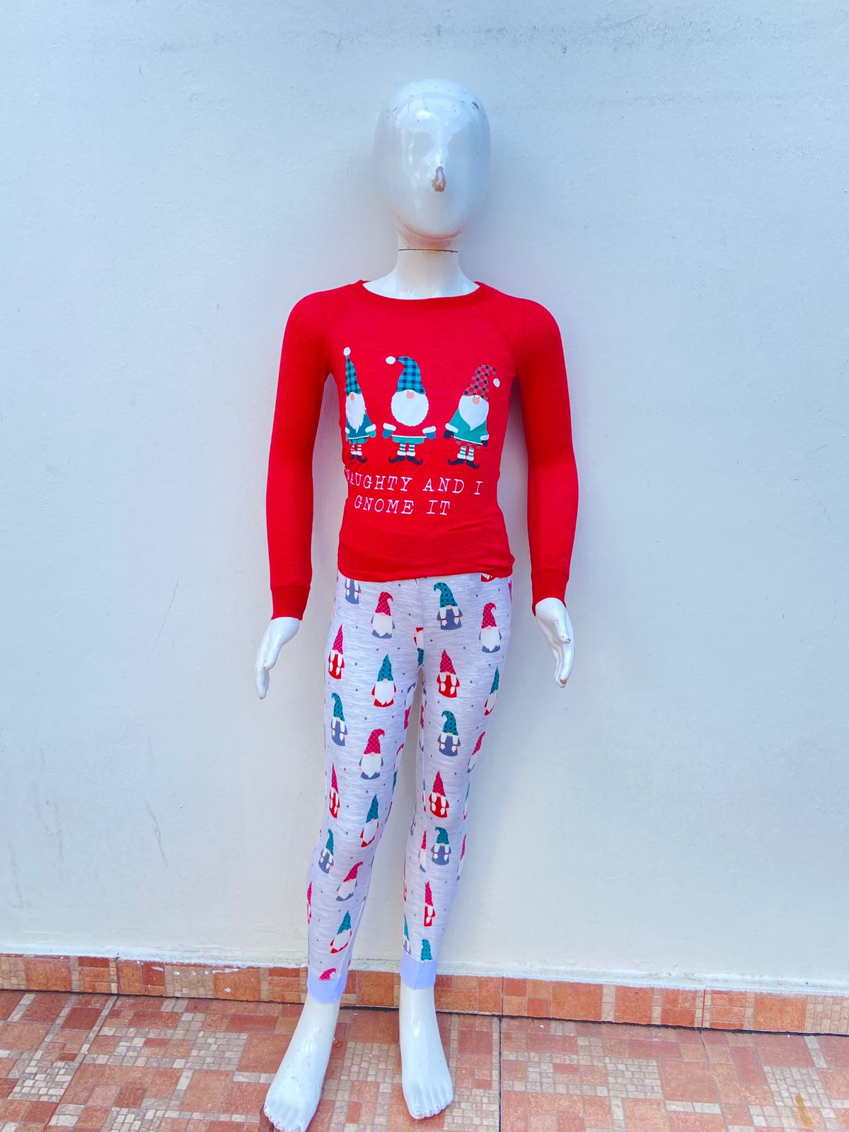 Conjunto/ Pijama Navidad rojo y gris, con estampados de muñequitos de duendes navideños y magos, con letras “NAUGHTY AND I GNOME IT” (Travieso(a) y lo gnomo).