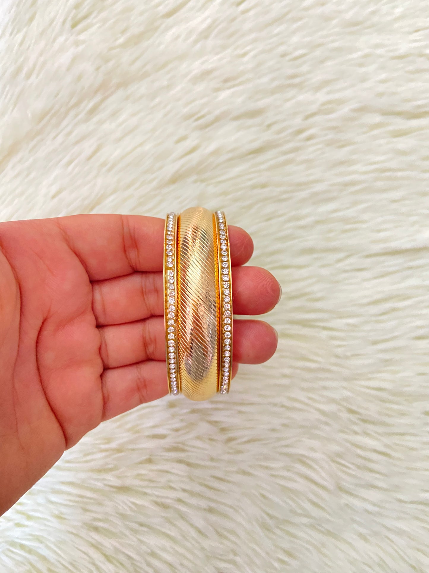 Pulsera en dolor dorado con detalles de piedras plateadas alrededor.
