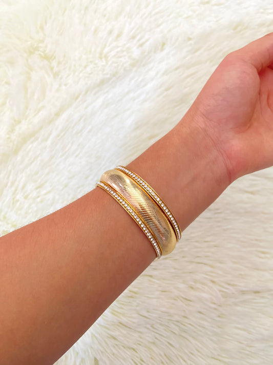 Pulsera en dolor dorado con detalles de piedras plateadas alrededor.