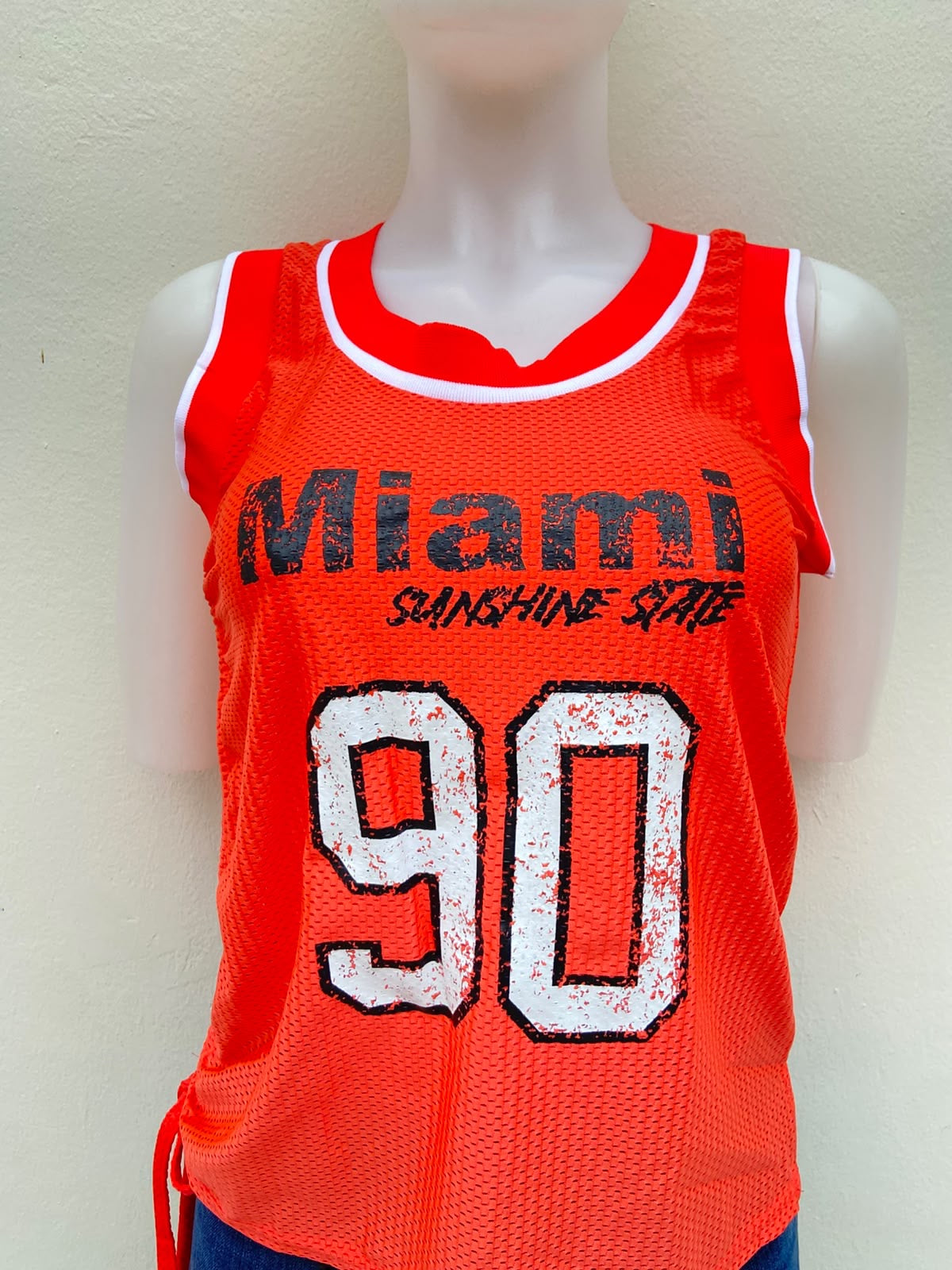Top/ franela color naranja neón, con letras MIAMI 90 en blanco y negro.