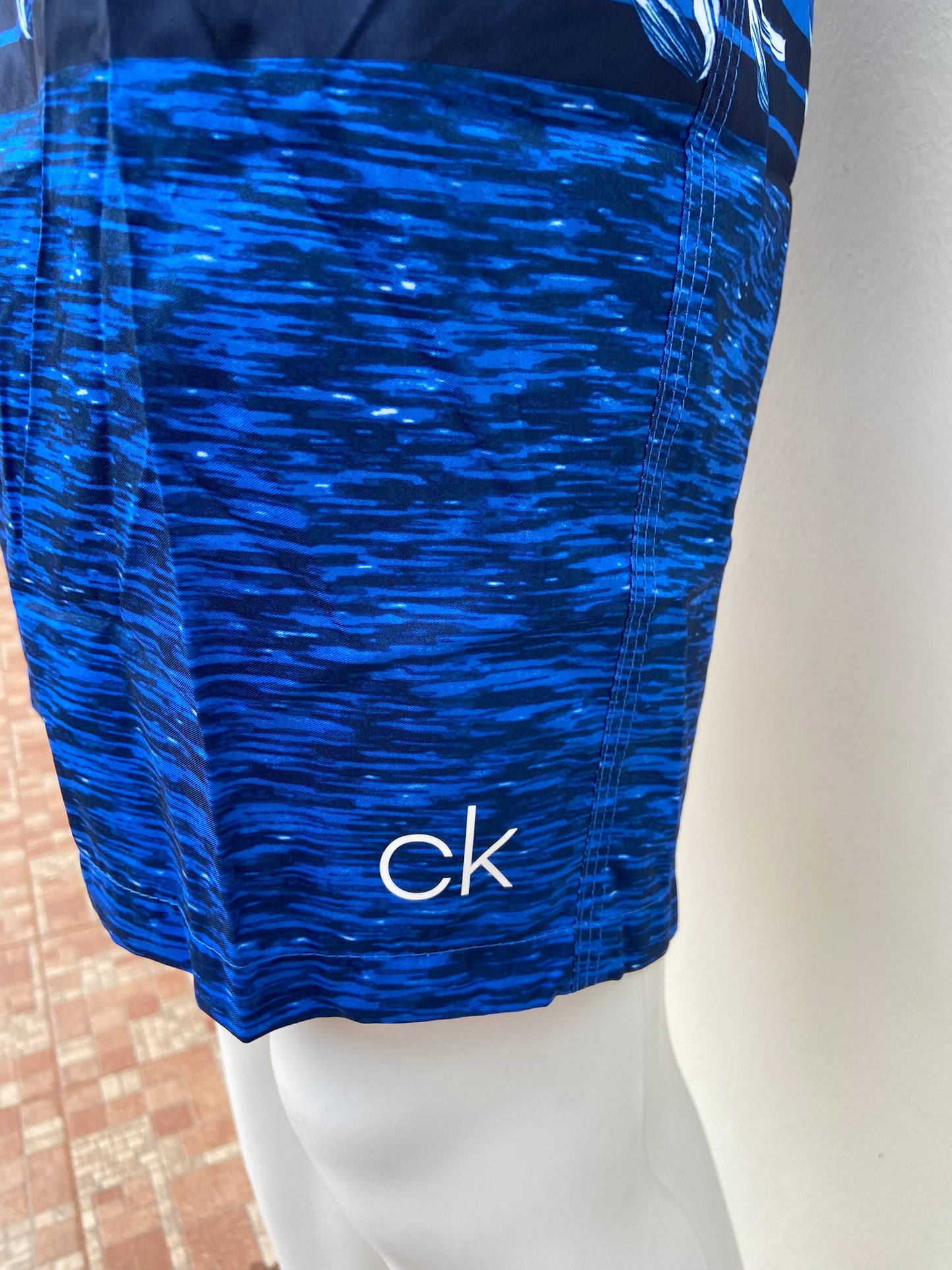 Bañador Calvin Klein original de color azul con diseño de flores azul con blanco rayas azul marino y parte de abajo degradado en tonos azules