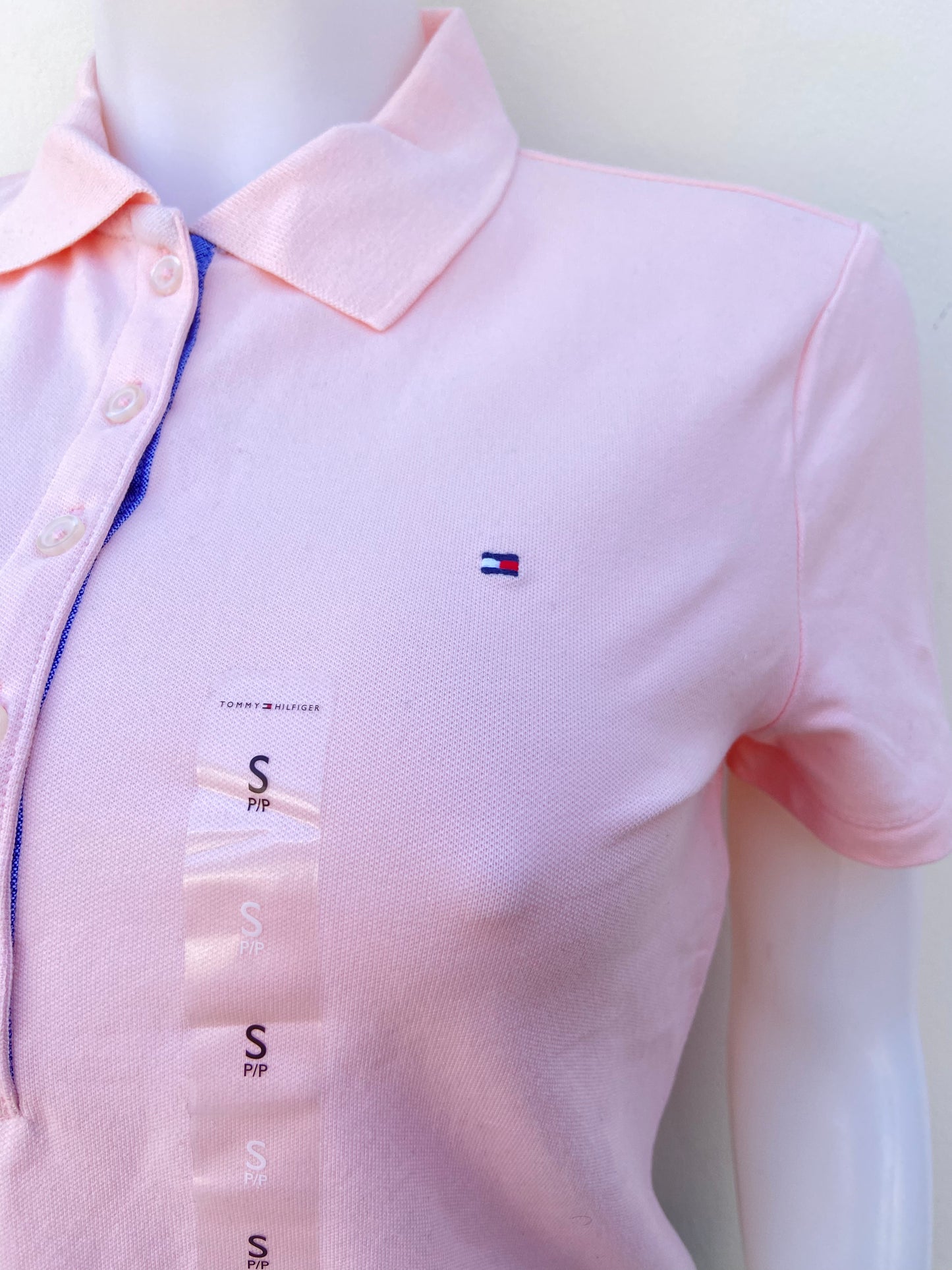 Polocher Tommy Hilfiger original rosado claro con botones en frente y logotipo de la marca.