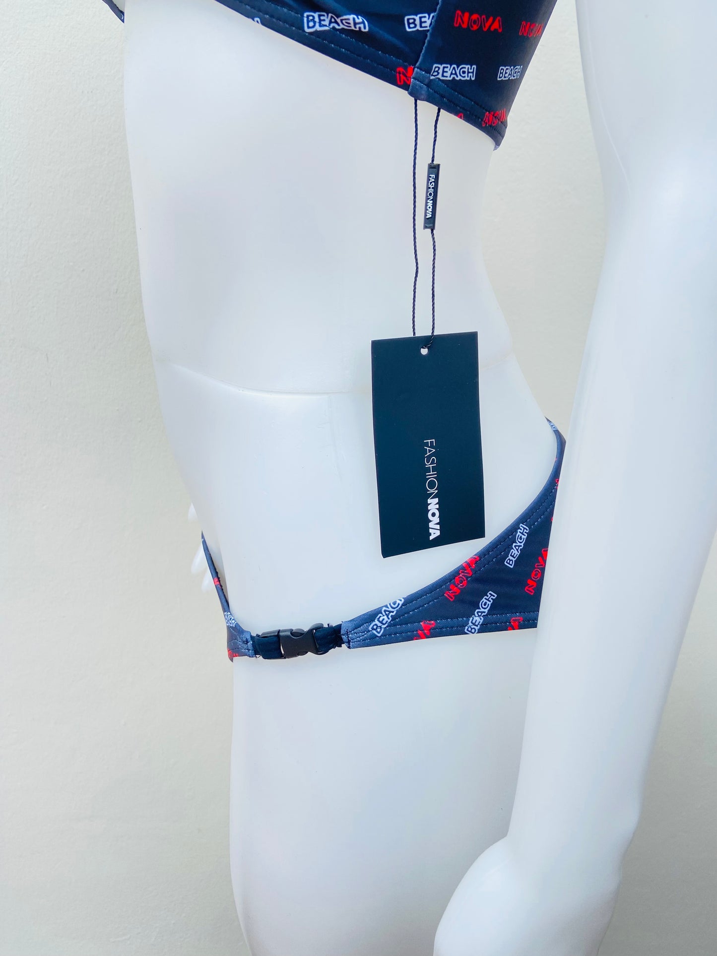 Biquini Fashion Nova original azul marino con abierto en la parte delantera y clicks negros, y letras en rojo y blanco BEACH NOVA.