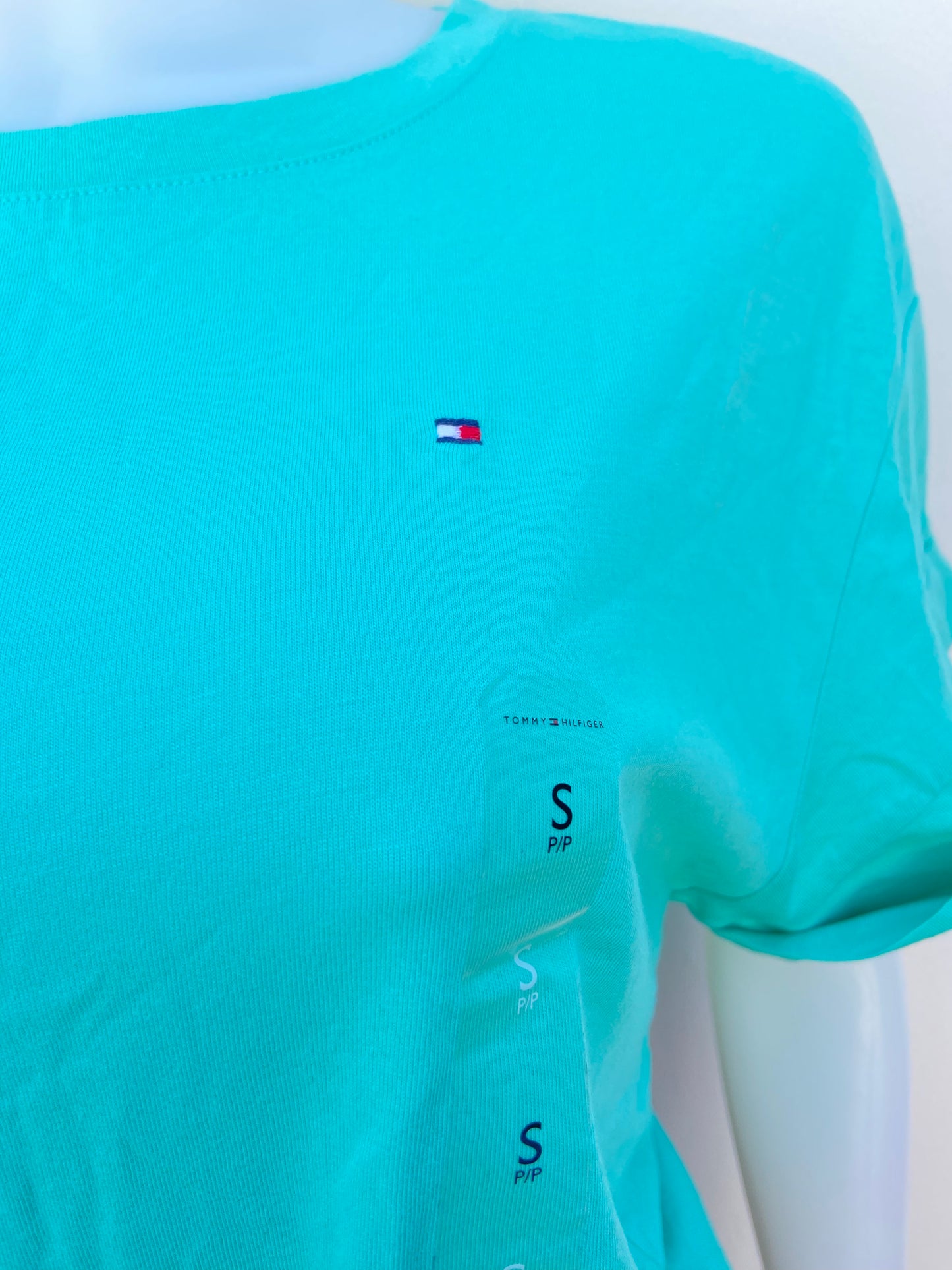 Blusa Tommy Hilfiger original verde aqua, con logotipo de la marca al lado y lazo ajustable en la parte delantera.