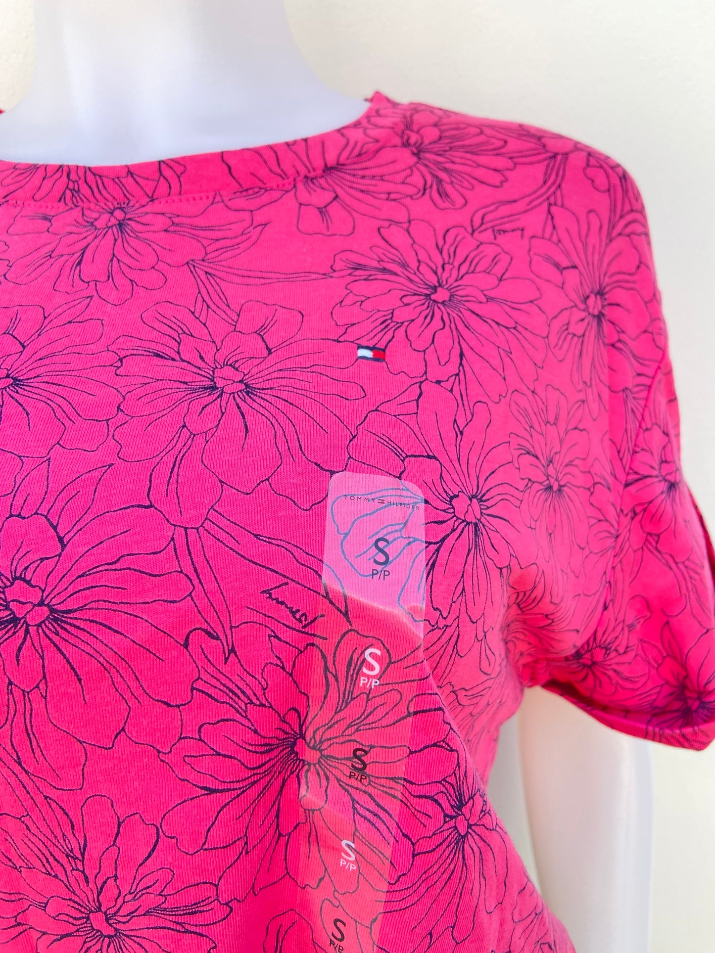Blusa Tommy Hilfiger original rosado fucsia con estampado de flores en color negro y lazo ajustable en la parte delantera.