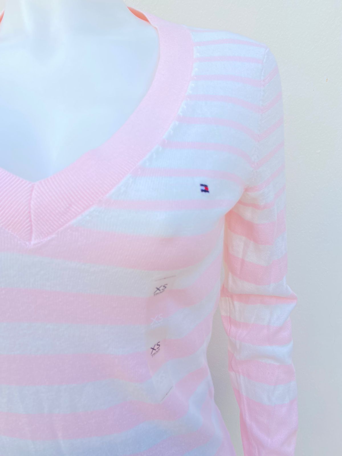 Suéter Tommy Hilfiger original rosado con rayas en color blanco y cuello en V, logotipo de la marca al lado.